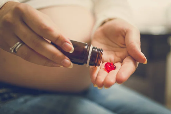 Крупним планом вагітна жінка на третьому триместрі, що тримає вітаміни в — стокове фото