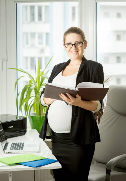 Snygg gravid affärskvinna poserar med filer på kontor — Stockfoto