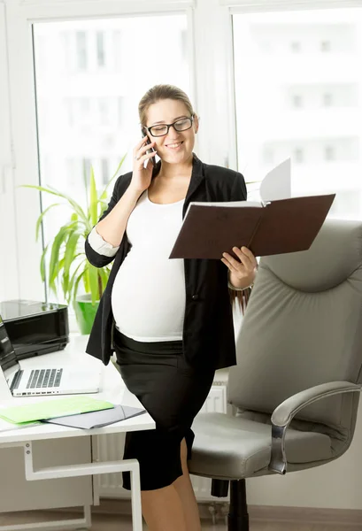 Pregnant businesswoman in black suit using mobile phone — Stock Photo, Image