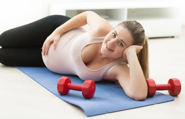 Mujer embarazada relajándose en la esterilla de fitness después de hacer ejercicio — Foto de Stock