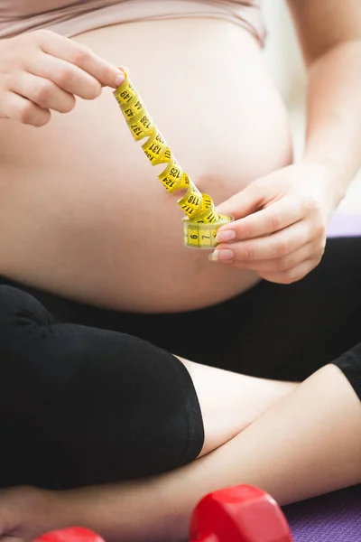 Foto close-up wanita hamil yang memegang pita pengukur — Stok Foto