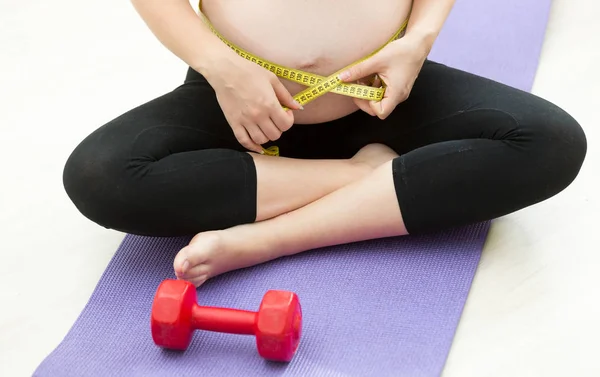 Zwangere vrouw buik met tape meten na de uitoefening op pasvorm — Stockfoto