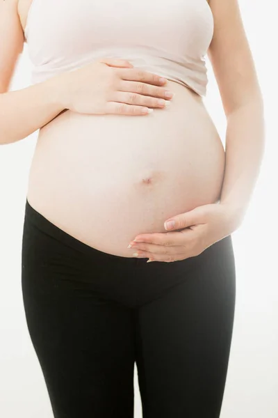 Mujer embarazada joven en ropa deportiva posando sobre fondo blanco —  Fotos de Stock