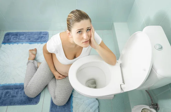 Porträt einer schwangeren Frau mit Vergiftung auf dem Boden sitzend — Stockfoto