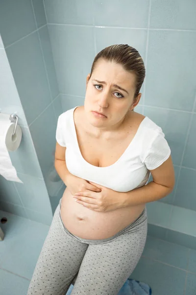 Retrato de mulher grávida chateada sentindo-se mal usando banheiro — Fotografia de Stock