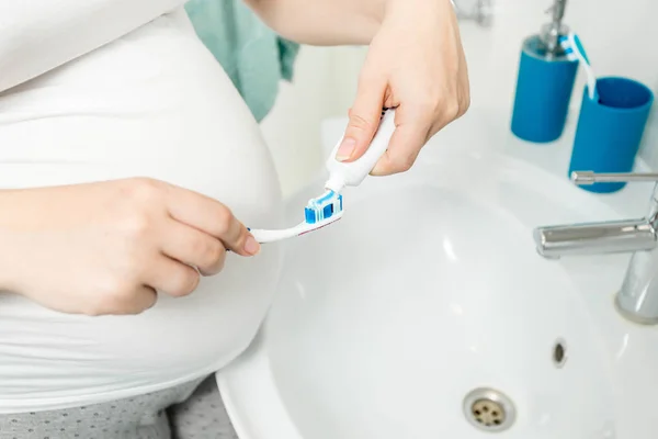 Close-up beeld van vrouw zetten tandpasta op de tandenborstel op bathr — Stockfoto