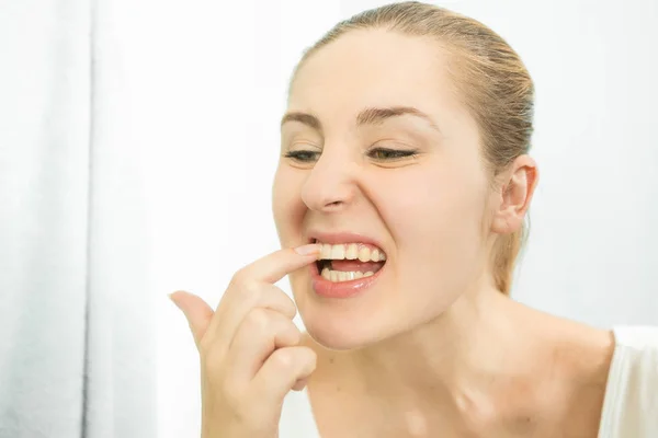 Porträt einer Frau, die mit dem Finger Lebensmittel pflückt, die in den Zähnen stecken — Stockfoto