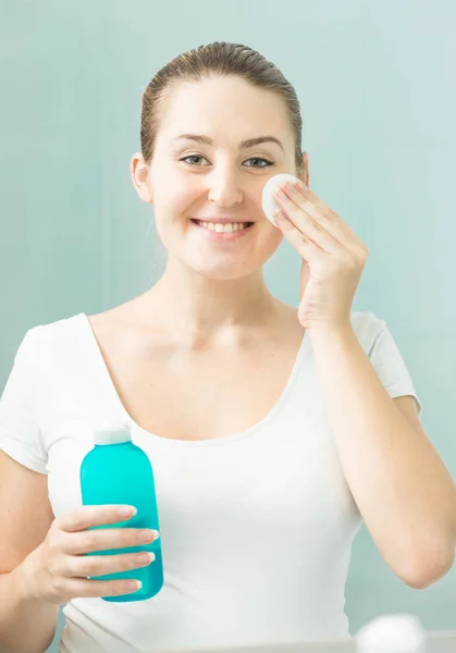 Porträtt av vackra leende kvinna rengöring ansikte med lotion — Stockfoto