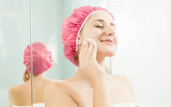 Retrato de cerca de una mujer joven usando crema facial —  Fotos de Stock