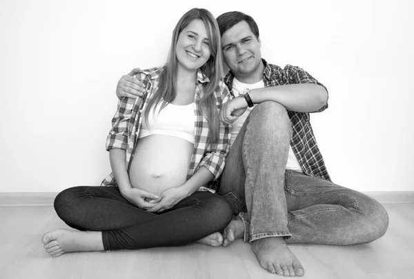 Černobílý portrét šťastný těhotná pár sedí na flo — Stock fotografie