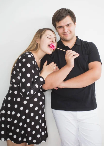 Funny portrait of young man holding lollipop and giving in to gi — Stock Photo, Image