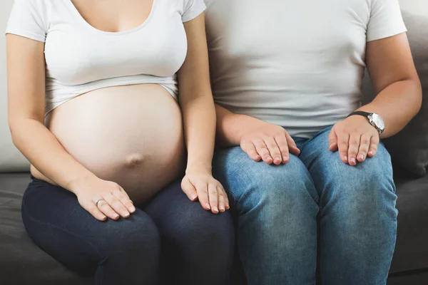 Casal grávida sentado no sofá ao lado um do outro — Fotografia de Stock