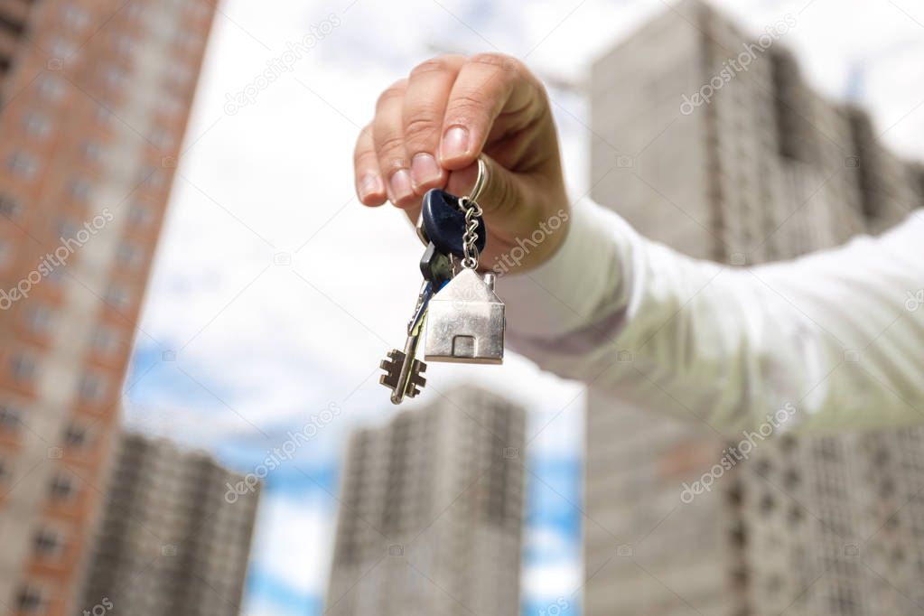 Closeup of young businessman hand holding keys from new home