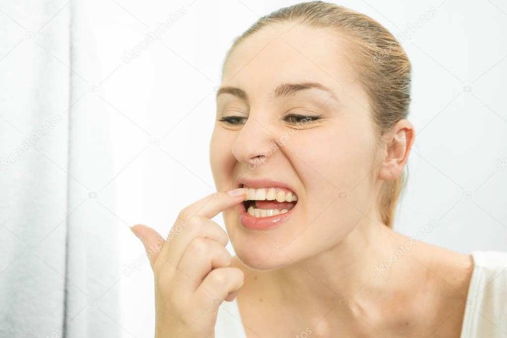 Portrait of woman picking food stuck in teeth with finger