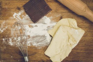 Oklava, çikolata, un ve ahşap tahta üzerinde yalan hamur