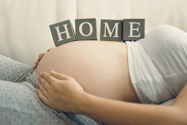Imagem de close-up da mulher grávida segurando palavra Casa na barriga — Fotografia de Stock