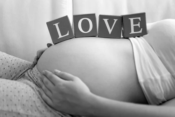 Černé a bílé image mladé těhotné ženy slovem láska na — Stock fotografie