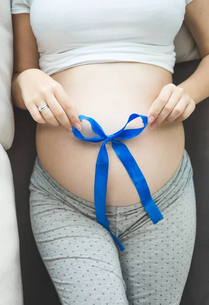 Foto close-up da mulher grávida deitada no sofá e segurando r azul — Fotografia de Stock