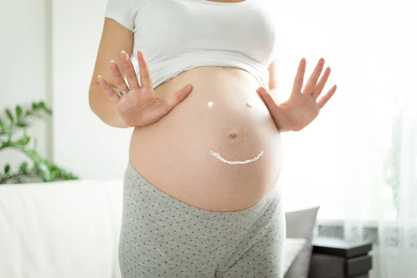 Mujer embarazada con sonrisa dibujada por la crema para las estrías en tu — Foto de Stock