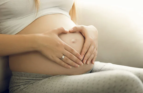 Zbliżenie zdjęcie opiekuńcze matki w ciąży dotykając brzucha — Zdjęcie stockowe