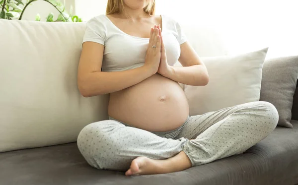 Bela jovem grávida se exercitando no sofá na sala de estar — Fotografia de Stock