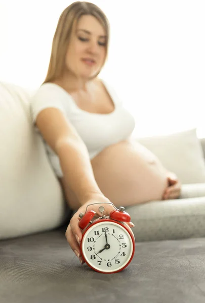 Tiro conceitual de mulher grávida sentada no sofá e segurando r — Fotografia de Stock