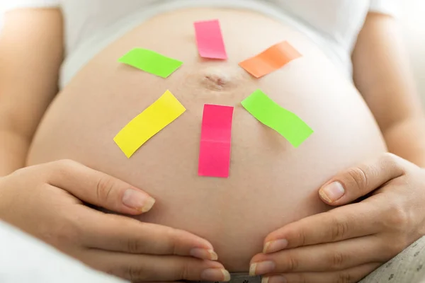 Unga gravid kvinna med memo klistermärke på magen — Stockfoto