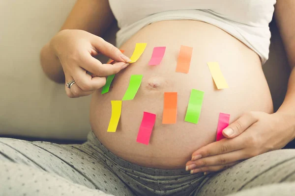 Vacker ung gravid kvinna som håller färgglada memo klistermärken — Stockfoto