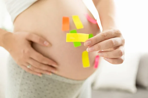 Närbild foto av gravid kvinna som håller färgglada klistermärken — Stockfoto