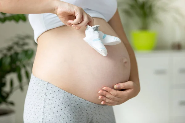 Closeup of pregnant woman pretending to walk with child socks on — Stock Photo, Image