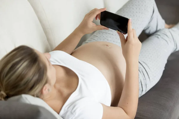 Närbild foto av gravid kvinna liggande på soffan och skriva meddelande — Stockfoto