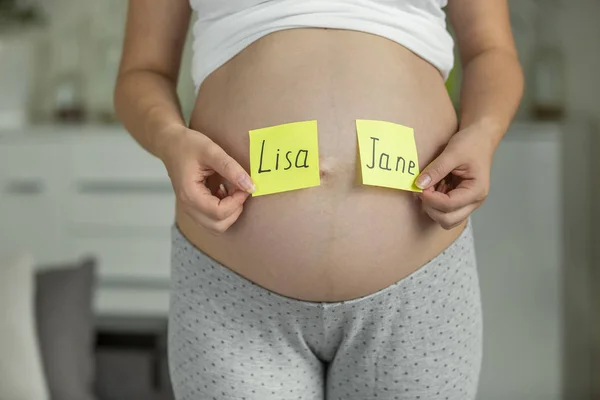 Schwangere wählt Baby-Namen auf dem Bauch — Stockfoto