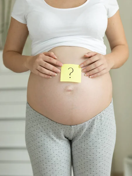 Encerramento da mulher grávida segurando ponto de interrogação desenhado no memo st — Fotografia de Stock