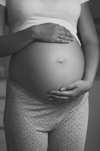 Zwart-wit close-up foto van zwangere vrouw hand in hand op — Stockfoto