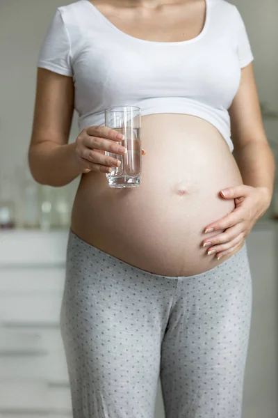 Unga gravid kvinna som håller glas vatten — Stockfoto