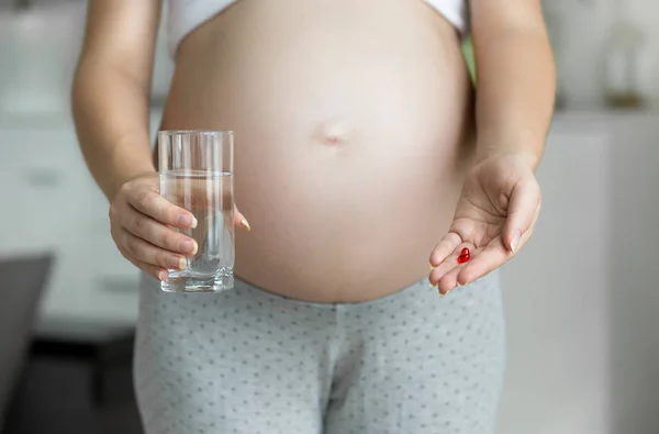 Imagem de close-up da mulher grávida segurando pílula na mão — Fotografia de Stock
