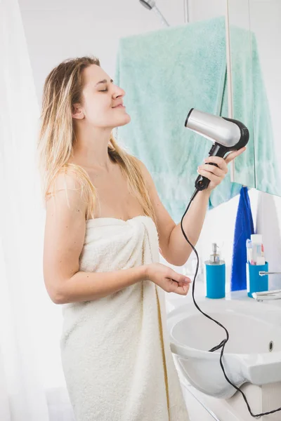 Mujer joven cantando mientras se seca el cabello en el baño — Foto de Stock