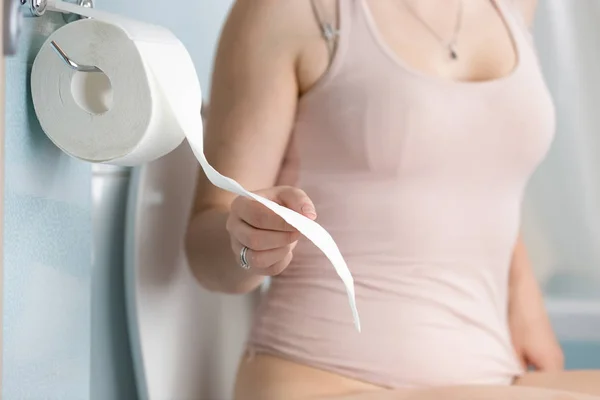 Imagen de primer plano de una mujer joven arrancando papel higiénico —  Fotos de Stock