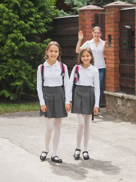 Mamma vinkar med handen till hennes döttrar går till skolan — Stockfoto