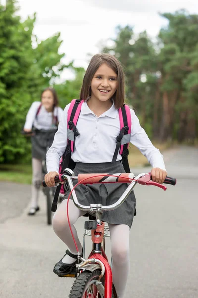 Heureuse fille souriante en uniforme scolaire à vélo — Photo