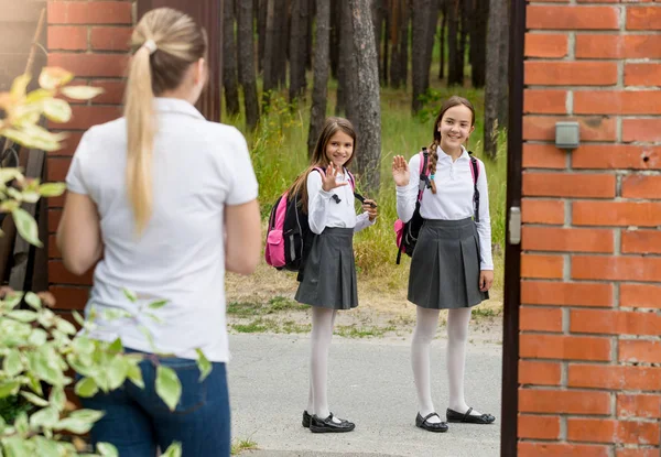 Joven madre despedir a sus hijos a la escuela y saludar a la —  Fotos de Stock