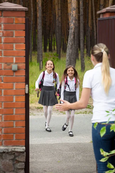 Две счастливые веселые девочки бегут к своей матери после школы — стоковое фото