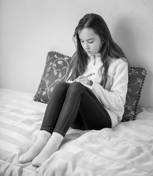 Černobílý portrét dospívající dívka dělat poznámky v deníku — Stock fotografie