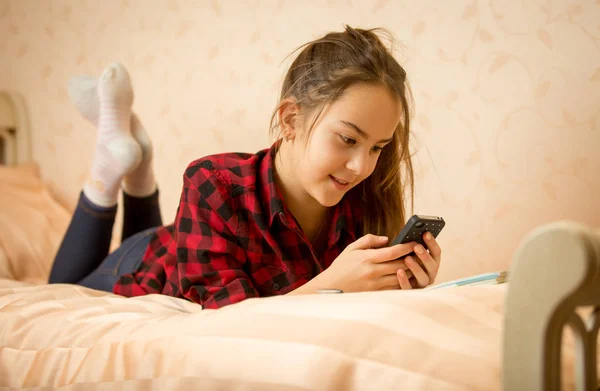 Retrato de linda adolescente acostada en la cama y escribiendo mensaje en —  Fotos de Stock