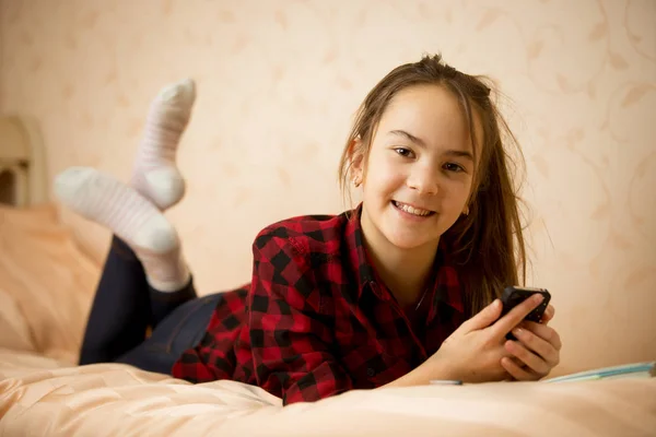 Retrato de hermosa sonrisa adolescente ling en la cama y el uso de —  Fotos de Stock