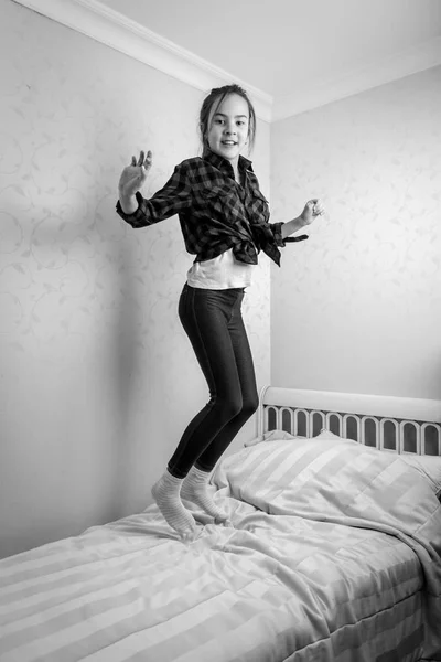 Черно-белая жизнерадостная девочка-подросток прыгает высоко в своей кровати — стоковое фото