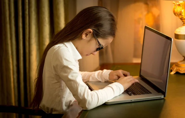 Skolflicka sitter bakom bordet och använder laptop på skåp — Stockfoto