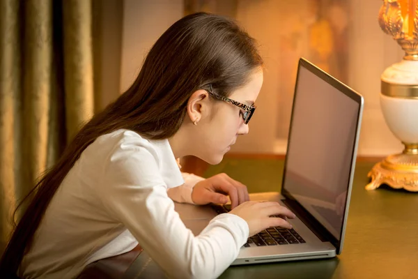 Retrato de chica adolescente con mala vista escribiendo mensaje en el ordenador portátil —  Fotos de Stock