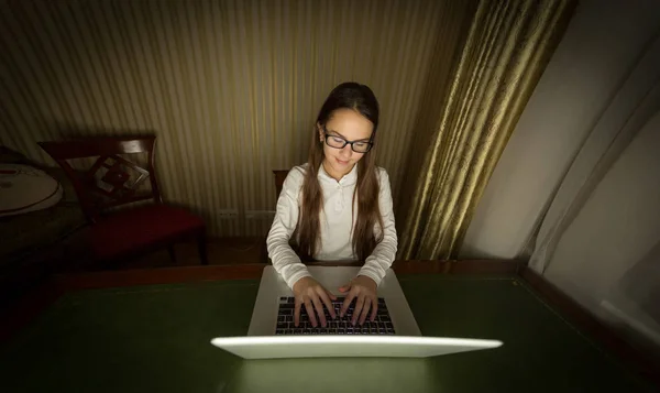 Menina sorridente em óculos usando laptop no final da noite — Fotografia de Stock