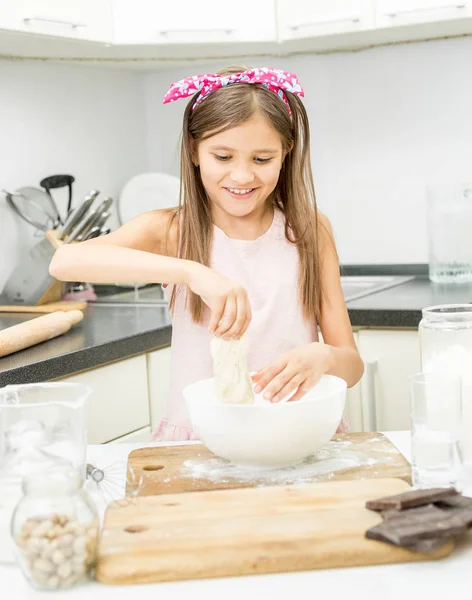 Bella bambina con fiocco rosa sui capelli facendo pasta su kitc — Foto Stock